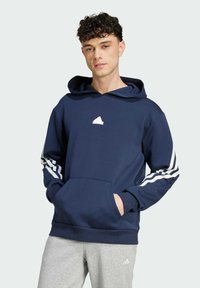 Námořnická modrá mikina s kapucí, která má na hrudi bílou grafiku a bílé pruhy na rukávech. Má přední kapsu a žebrovaný lem.