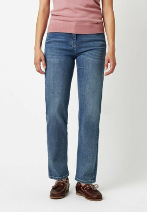 Light blue denim jeans with a straight-leg cut, subtle fading, and five-pocket design. Paired with brown lace-up shoes.