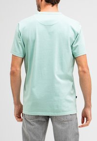Mint green short-sleeve T-shirt with a round neckline, featuring a plain design and soft texture, paired with light gray denim jeans.