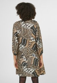 Druckkleid mit einer Mischung aus Hahnentrittmuster und geometrischen Mustern in Braun, Schwarz und Creme. Mit mittellangen Ärmeln und lockerer Passform.