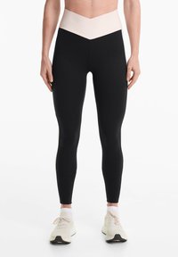 Magas derekú leggings fekete testtel és kontrasztos világos rózsaszín, V-alakú derékrésszel. Rugalmasságot és sima tapintást biztosító anyagból készült.