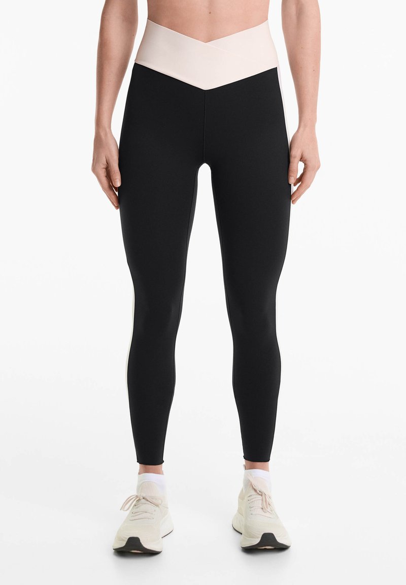 Magas derekú leggings fekete testtel és kontrasztos világos rózsaszín, V-alakú derékrésszel. Rugalmasságot és sima tapintást biztosító anyagból készült.