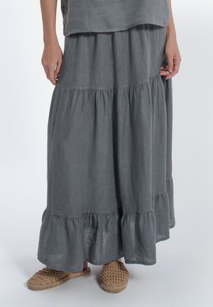 Jupe maxi en lin gris avec des volants superposés au bas, associée à des chaussures slip-on tissées beiges. La jupe a une coupe ample et décontractée.
