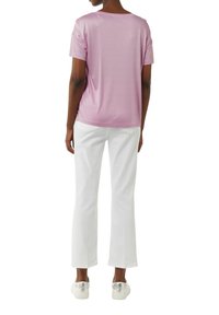 Pink short-sleeve t-shirt made of soft fabric, paired with white straight-leg pants and silver accented sneakers.