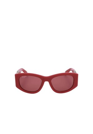 Occhiali da sole rossi a forma di occhio di gatto con montatura spessa e lenti colorate, con un logo discreto nell'angolo in alto a sinistra della lente.