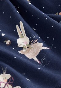 Marineblauer Stoff mit verspielten Illustrationen eines Kaninchens im Kleid und Einhörnern, geschmückt mit Sternen und Schneeflocken. Weiches, strukturiertes Material.