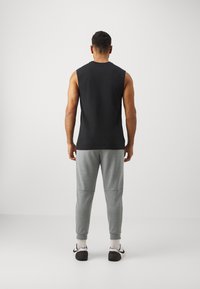 Black sleeveless shirt and gray tapered sweatpants. Shirt has a crew neck; pants are elasticated at the ankles with side pockets.
