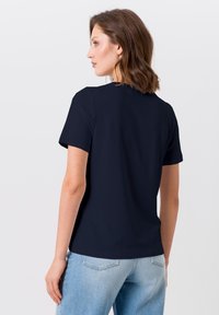 Marineblaue kurzärmelige T-Shirt mit einem schlichten Design, rundem Halsausschnitt und weichem Material, kombiniert mit hellblauen Jeans.