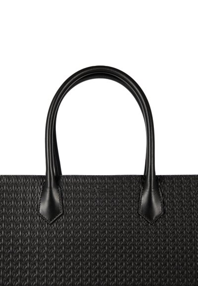 Zwarte geweven draagtas met gladde leren handgrepen en hoekige accenten, voorzien van een textuurrijk lichaam met een geometrisch patroon.