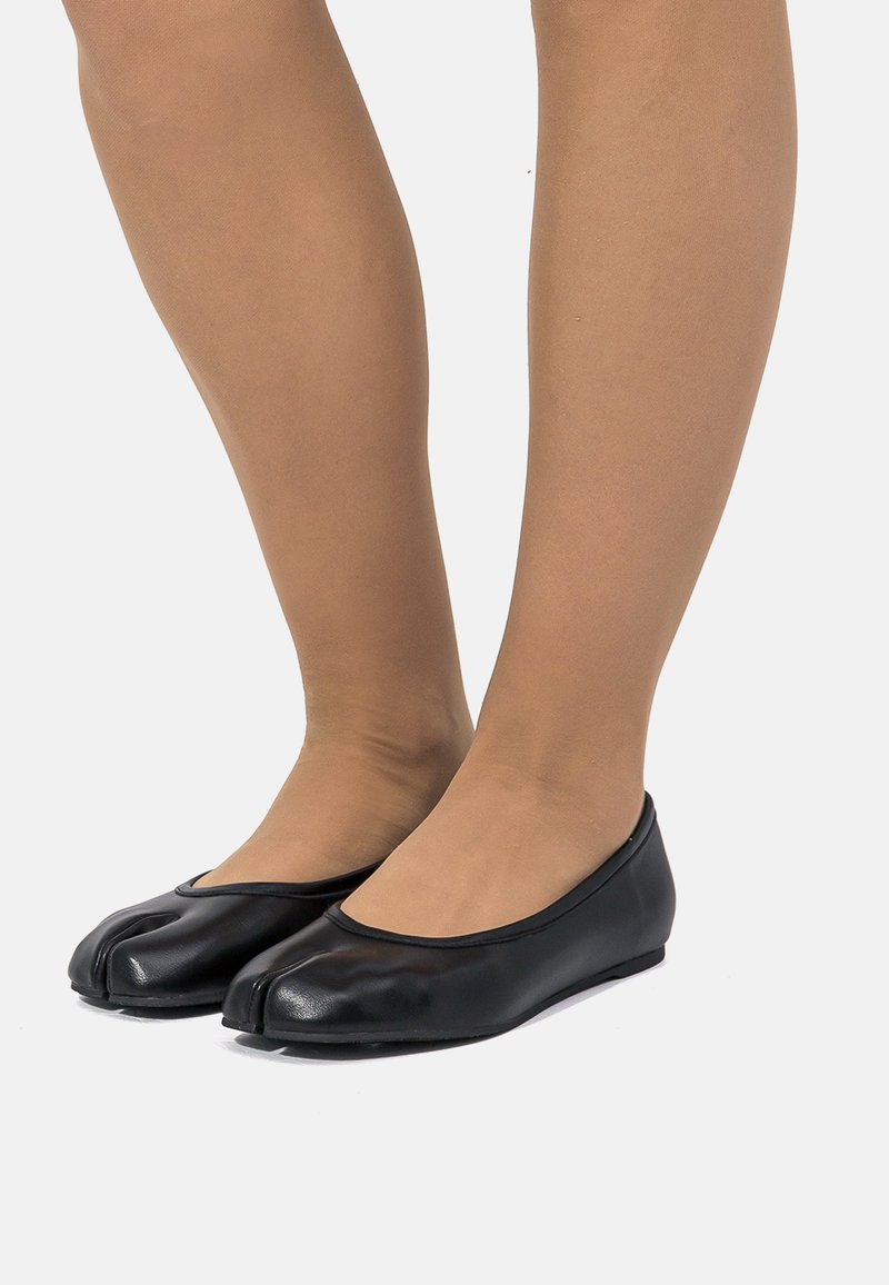 Ballerine nere in pelle con un design unico sulla punta. Texture liscia, bordo arrotondato e forma minimalista. Nessuna ferramenta o dettagli visibili.