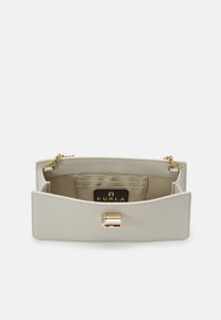 Hellbeige Lederhandtasche mit strukturiertem Finish, goldenen Beschlägen und einem magnetischen Verschluss. Das Innere verfügt über mehrere Kartenfächer und ein Logotag.