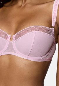 Rosa bh med nätdesign och spetskant. Kuporna är semi-justerbara med bygel och dekorativa band. Slät textur genom hela.