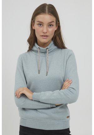 Helles blaues Kapuzensweatshirt aus weichem Stoff mit Schalkragen, ausgestattet mit Kordelzügen und einem kleinen Markenschild am Saum.