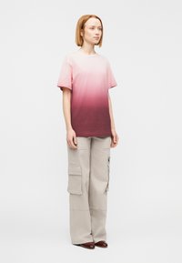 Βαμβακερό μπλουζάκι με διαβάθμιση από ροζ σε μοβ, κοντά μανίκια, σετ με μπεζ παντελόνι τύπου cargo με μεγάλες τσέπες και άνετη εφαρμογή.