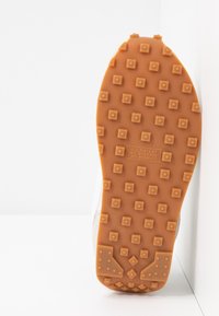 Gummisula med en texturerad, orange yta som har fyrkantiga och diamantmönster; inkluderar patentdetaljer.