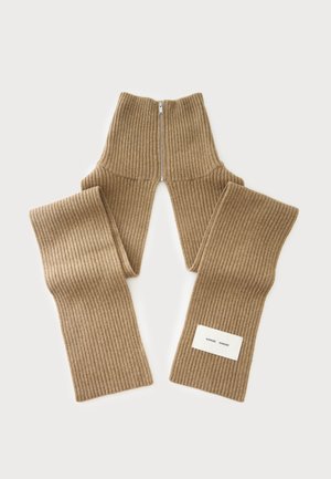Écharpe en maille côtelée beige avec une fermeture éclair centrale et une petite étiquette blanche à une extrémité.