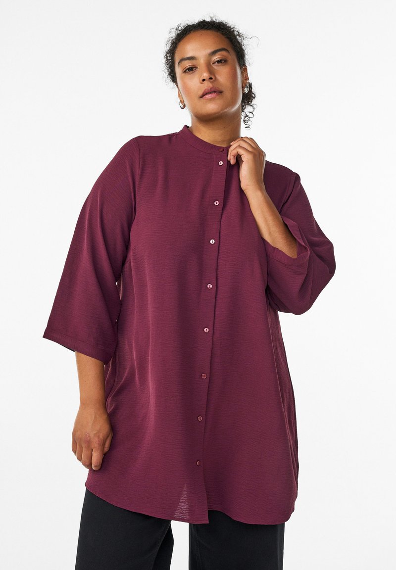 Maroon button-up shirt with a round neckline, three-quarter sleeves, and a textured fabric. Features a relaxed fit and subtle sheen.