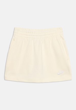 Crèmekleurige Nike-rok met elastische tailleband en zijzakken, met een klein wit Nike-logo vlak bij de zoom aan de rechterkant.