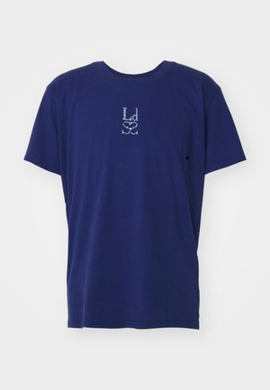 Marineblå T-shirt med korte ærmer og et lille hvidt abstrakt mønster centralt på brystet, ensfarvet baggrund.