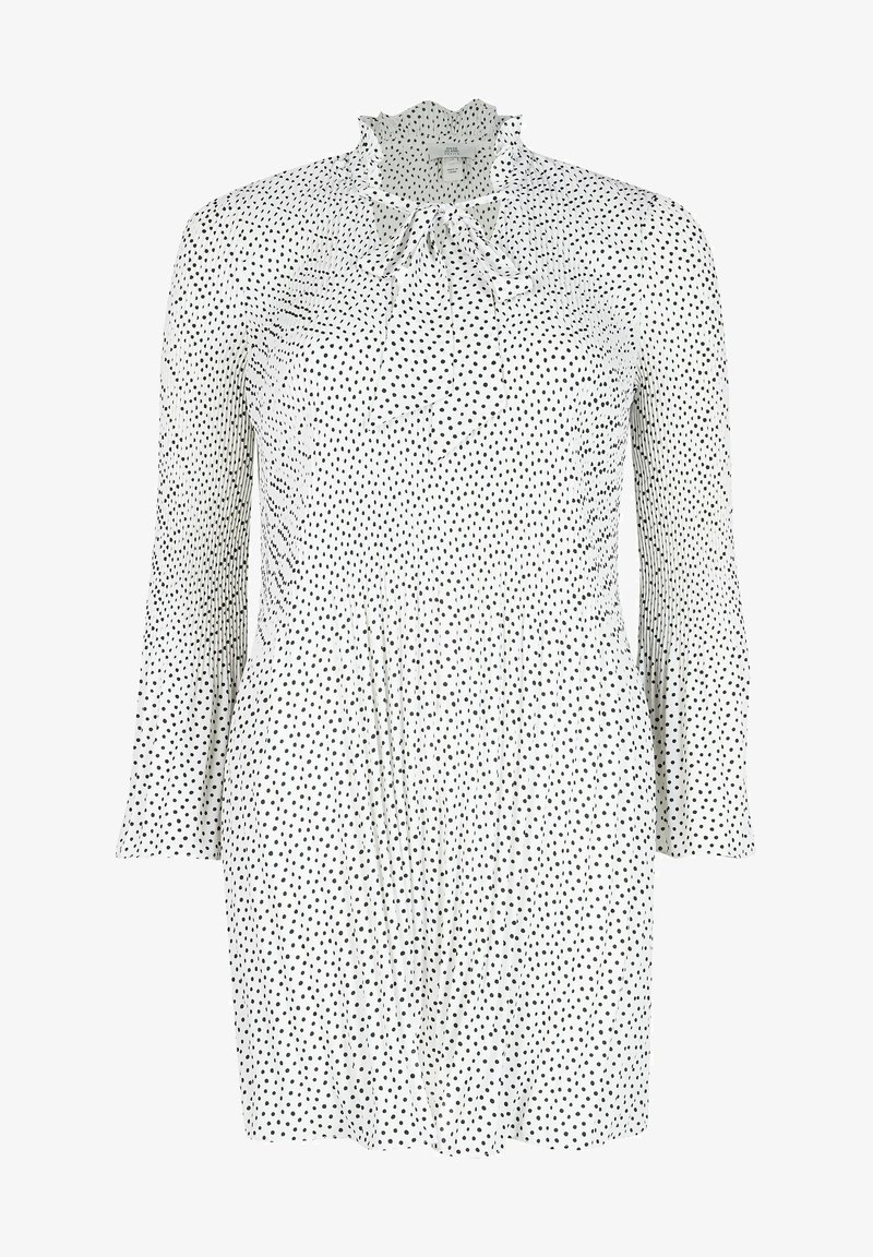 Weißes Kleid mit schwarzen Punkten, das lange Ärmel, einen gerafften Ausschnitt und ein tailliertes Oberteil hat, das sich an der Taille ausstellt.