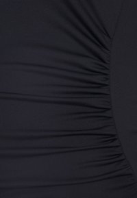 Tecido preto com textura franzida, apresentando pregas horizontais. O material parece liso, com um leve brilho. Sem hardware ou padrões visíveis.