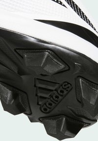 Crno-bijela potplat športskog obuća s teksturiranom gumom, istaknutim čavlima za prianjanje i utisnutim logotipom. Oblikovan za performanse.