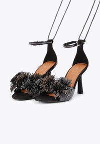 Czarne sandały na wysokim obcasie z zamszowej cholewki, ozdobnym paskiem na kostce zdobionym kryształami oraz teksturowanymi kwiatowymi akcentami na palcach.