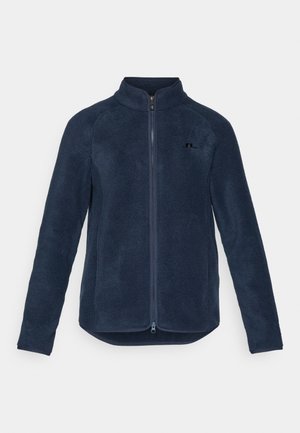 Chaqueta de forro polar en color navy con cierre de cremallera en la parte delantera, alto cuello, manga larga y dobladillo curvado; presenta un pequeño logo negro en el pecho.