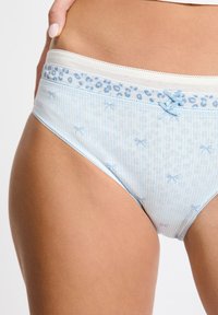 Mutandine in cotone azzurro chiaro con un motivo a righe, dotate di una fascia elastica bianca a contrasto e delicati accenti a fiocco.