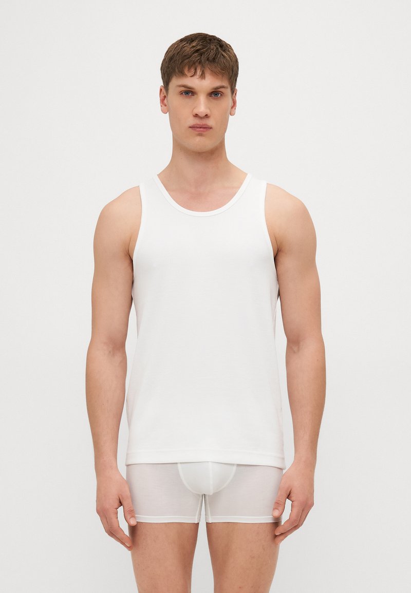 White cotton tank top with a round neckline, paired with sheer white boxer shorts. Fitted design, smooth texture, no visible patterns.