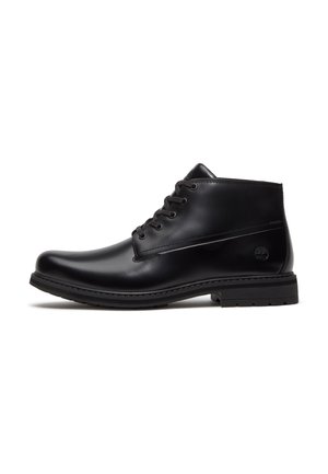 Bottine noire en cuir à lacets, talon bas et semelle en caoutchouc, avec des détails cousus et un logo de marque discrètement embossé sur le côté.