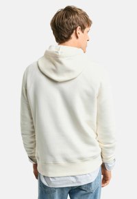 Hoodie w kolorze off-white, wykonany z bawełny, o luźnym kroju, z prążkowanymi mankietami i dołem, charakteryzujący się miękką fakturą i minimalnym designem.