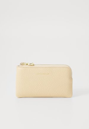 Portafoglio in pelle beige con superficie texturizzata, chiusura con zip, accessori in oro e nome del marchio impresso. Forma rettangolare compatta.