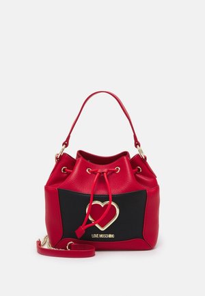 Red and black bucket bag with gold heart emblem, drawstring closure, top handle, and detachable shoulder strap.