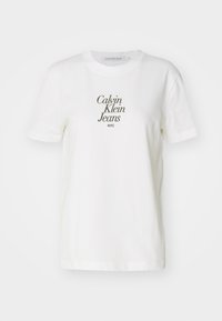 Tricou alb din bumbac, cu mâneci scurte, având inscripționat "Calvin Klein Jeans NYC" în gri închis, cu un font serif modern.