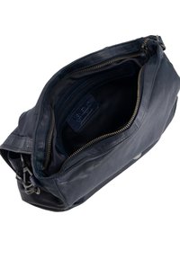 Námořnická kožená taška s jedním popruhem, obsahující hlavní přihrádku na zip, vnitřní kapsy a texturovaný povrch.