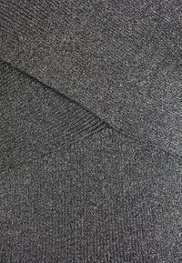 Metaliczna czarna tkanina o drobnej, teksturowanej dzianinie. Posiada wzór w krzyż i subtelny blask oraz miękką prążkowaną krawędź.