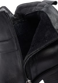 Bottine en cuir noir avec fermeture à glissière, doublure intérieure douce et surface extérieure texturée. Design à talon plat robuste.
