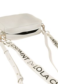 Borsa a tracolla bianca in pelle con superficie texturizzata, chiusura con zip e tracolla regolabile con lettering nero. Dettagli in metallo color argento.