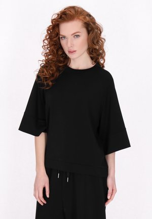 Sort oversized t-shirt med korte, brede ærmer og rund hals, lavet af blød stof, der har en afslappet pasform og et enkelt design.