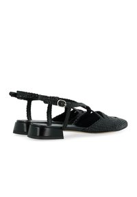 Scarpe nere intrecciate con tacco piatto, design aperto e cinghie incrociate. Texture in pelle con una leggera lucentezza e dettagli con fibbia regolabile.