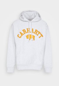 Hellgrauer Hoodie mit einer vorderen Kängurutasche, weißen Schnürsenkeln und dem Text "CARHARTT" über einem gelben Büffellogo auf der Brust.