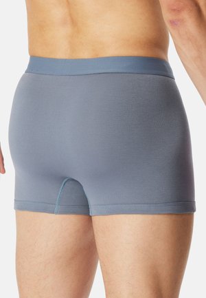 Man wearing fitted gray boxer briefs, showing waist, hips, and upper thighs against a plain white background.