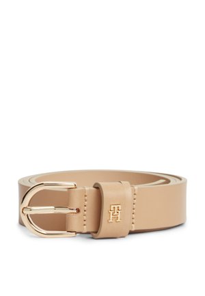 Kremasti kožni remen s zlatnom kopčom i malim zlatnim logotipom "TH" na petlji remena, namotan na bijeloj pozadini.