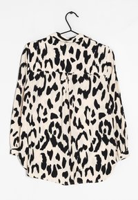 Camicia a maniche lunghe con un design a macchie di leopardo nero e crema. Realizzata in un tessuto morbido con orlo curvo e polsini con bottoni.