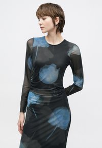 Šaty s dlouhým rukávem z průsvitné černé látky s modrými květinovými vzory, přiléhavý střih a řasení v pase. Hladká textura.