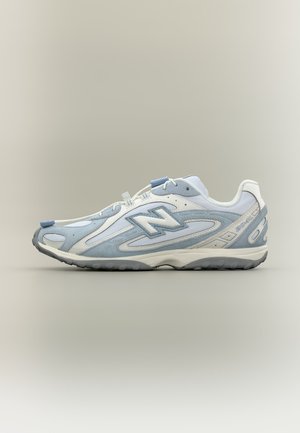 Baskets athlétiques bleu clair et blanc avec des lacets blancs, une semelle grise et le logo "N" sur le côté, présentées de profil sur fond neutre.