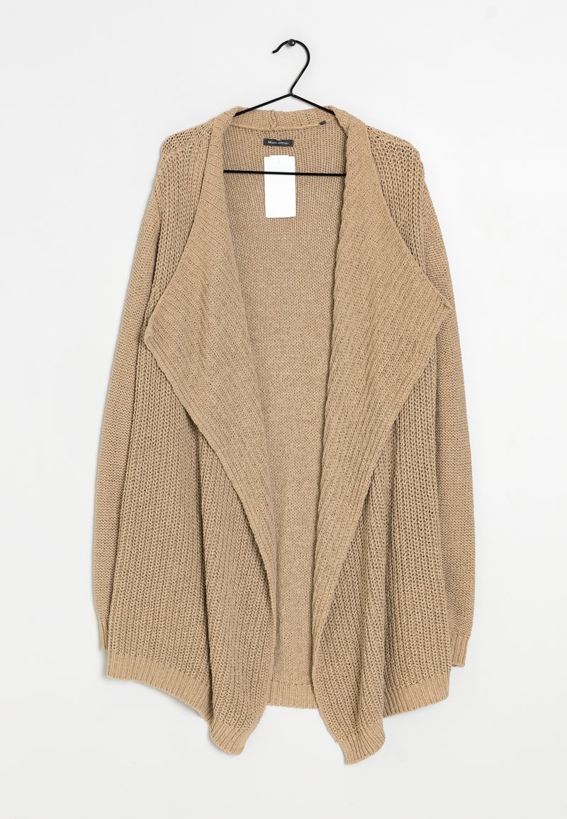 Cardigan beige lavorato a maglia aperto davanti con ampi revers appeso a un gancio nero su uno sfondo bianco.