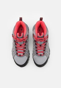 Szare buty trekkingowe z czerwonymi sznurowadłami i akcentami. Cholewka z siateczki i zamszu, wyściełany kołnierz oraz gumowa podeszwa z wzorami zapewniającymi przyczepność.