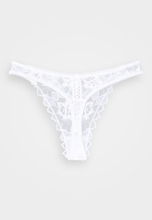 Witte kanten string met bloemmotief. Heeft golvende randen en een decoratieve voorkant met kruislings detail. Zacht, lichtgewicht materiaal.